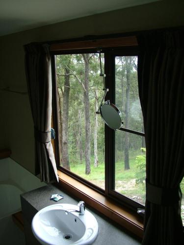 a bathroom with a window with a sink and a mirror at Sacred Mountain Retreat in Nambucca Heads