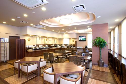 Hotel Route-Inn Nobeoka Ekimae في نوبيوكا: غرفة طعام مع طاولات وكراسي في مطعم