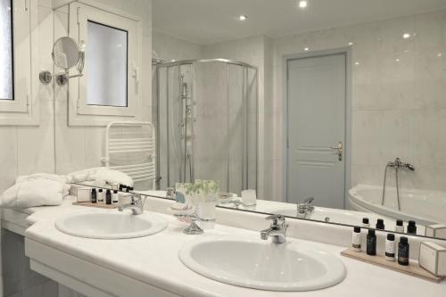 a bathroom with two sinks and a large mirror at Athens Atrium Hotel & Jacuzzi Suites in Athens
