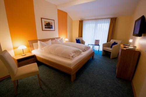 a hotel room with a bed and a chair at Hotel Garni Zur Alten Post in Lembruch