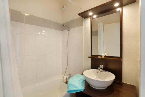 a bathroom with a sink and a tub and a mirror at Résidence Néméa Les Chalets Du Belvédère in Font-Romeu