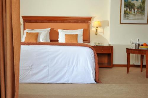 a bedroom with a bed with white sheets and pillows at Athens Atrium Hotel & Jacuzzi Suites in Athens