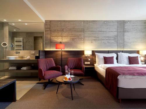 a hotel room with a bed and two chairs and a table at Hostellerie Stafelter in Walferdange