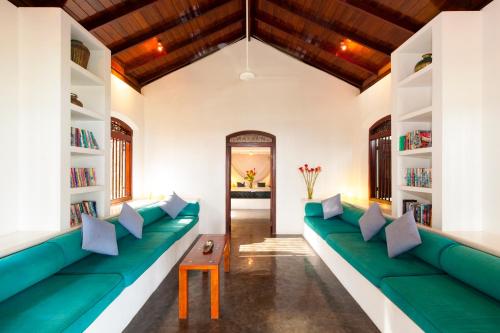 a room with a green couch and bookshelves at Apa Villa Thalpe in Unawatuna