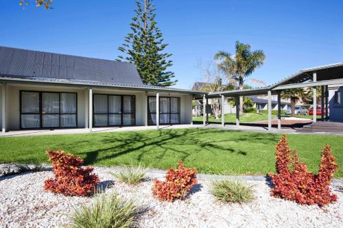 a house with a yard with red plants at Auckland Airport Kiwi Motel in Auckland