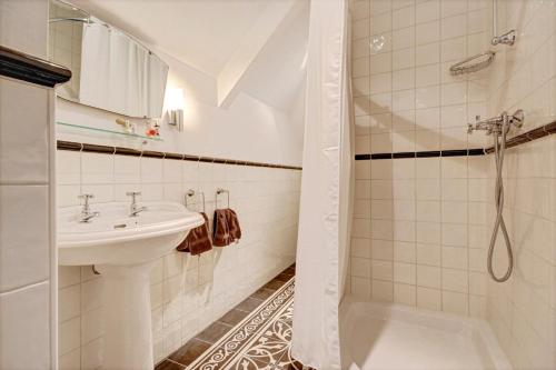 een witte badkamer met een wastafel en een douche bij 't Heerenhuys in Wageningen