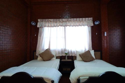 2 Betten in einem Zimmer mit Fenster in der Unterkunft Baan Kaewta in Chiang Mai