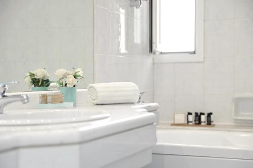 a white bathroom with a sink and a bath tub at Athens Atrium Hotel & Jacuzzi Suites in Athens