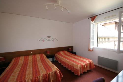 1 dormitorio con 2 camas y ventana en Logis Hôtel Relais Paris Bale - Restaurant La Mangeoire en Montieramey