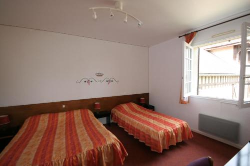 a bedroom with two beds and a window at Logis Hôtel Relais Paris Bale - Restaurant La Mangeoire in Montieramey