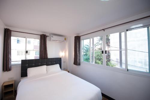 a bedroom with a white bed and two windows at Hoppers Place Donmuang in Bangkok