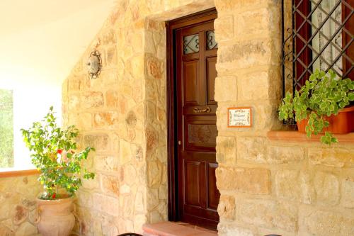 un muro in pietra con una porta in legno e piante in vaso di Casale Orioles a Torretta