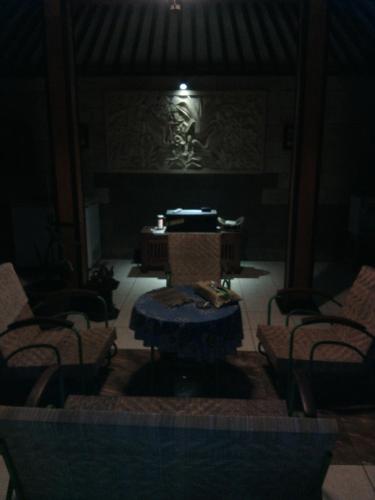 a dark room with a table and chairs and a piano at Rakai Garung in Yogyakarta