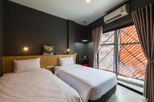 a bedroom with two beds and a large window at Srisuksant Square in Krabi town