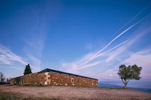 a brick building on top of a hill with a tree at Quartéis de Santa Justa in Cerquido