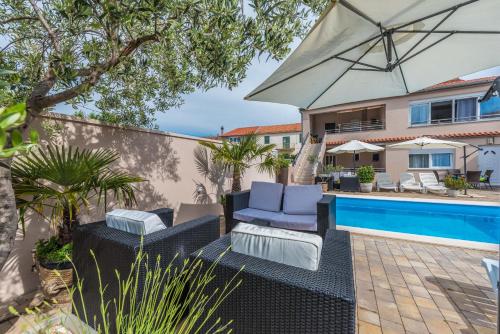un patio con sillas y una sombrilla junto a la piscina en Apartments Nika & Karla, en Bibinje