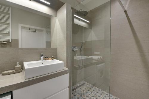 a bathroom with a sink and a glass shower at INA Rent - Tre Mare Apartamenty in Gdańsk