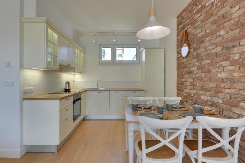 a kitchen with a brick wall and a table and chairs at INA Rent - Tre Mare Apartamenty in Gdańsk