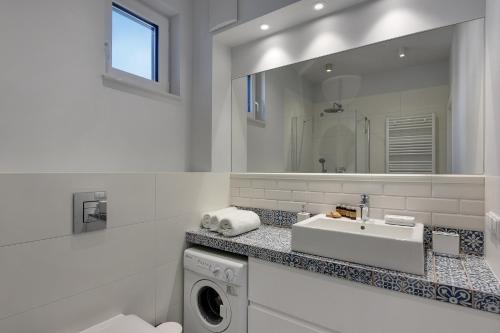 a bathroom with a sink and a washing machine at INA Rent - Tre Mare Apartamenty in Gdańsk