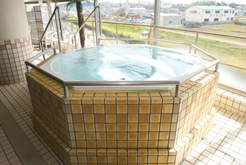 a hot tub in a room with a window at Route Inn Grantia Komaki in Komaki