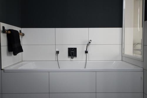 a white bathroom with a bath tub with a faucet at Weimar Central Artist Loft - 120 m2 in Weimar