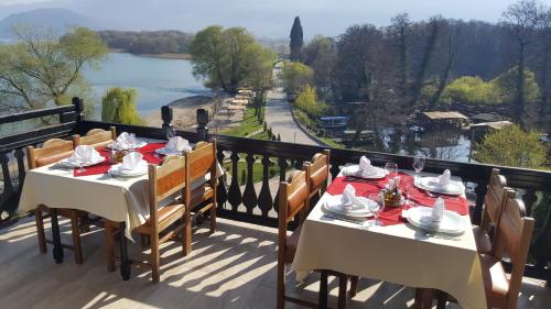 a balcony with tables and chairs with a view of a river at Hotel St. Naum in Ljubaništa