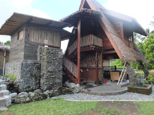a house with a thatched roof and a staircase at Uma Nirmala Aling-Aling in Singaraja