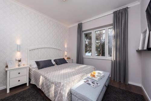 a white bedroom with a bed and a window at Sunset Beach Apartment in Zadar