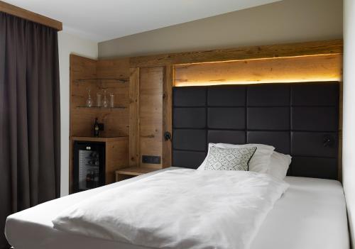 a bedroom with a white bed with a wooden headboard at Hotel Bütgenbacher Hof in Butgenbach