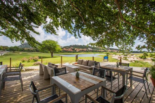 a wooden deck with tables and chairs and a view of a field at Blue Bay Lodges in Willemstad