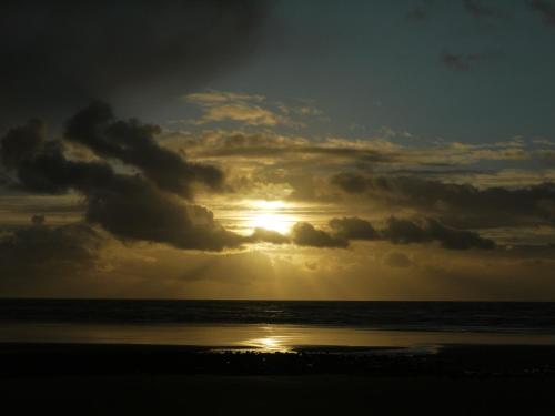 a sunset on the beach with the sun hiding behind clouds at Seascape in Barmouth