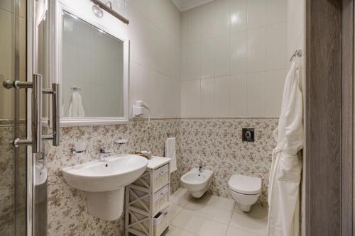 a white bathroom with a sink and a toilet at Gostiny Dvor Hotel in Kharkiv