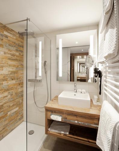 a bathroom with a sink and a shower with a mirror at Hotel Bütgenbacher Hof in Butgenbach