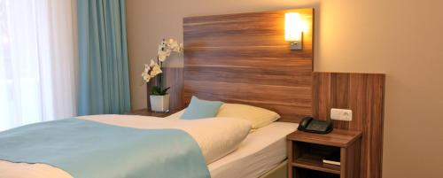 a bedroom with a bed with a wooden head board at Waldhotel Bad Soden in Bad Soden am Taunus