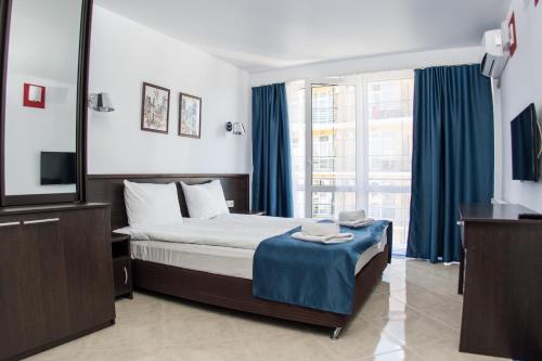 アドレルにあるHotel Marmarisのベッドルーム(ベッド1台、テレビ、青いカーテン付)