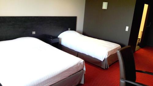 two beds in a hotel room with white sheets at Hôtel du Casino de Capvern in Capvern