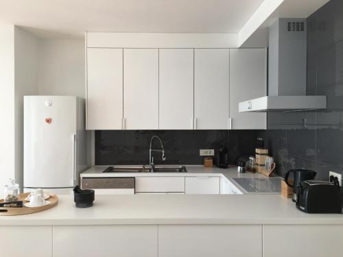 uma cozinha branca com um lavatório e um frigorífico em K Residence Zadar apartment em Zadar