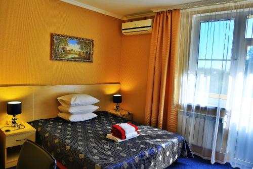 a hotel room with a bed with pillows and a window at Sibir Mini-hotel in Adler