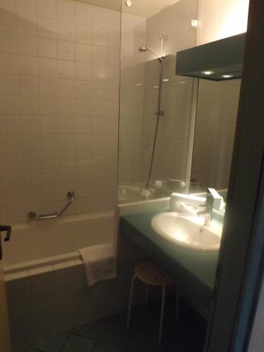 a bathroom with a sink and a tub and a mirror at Les Portes de la Vallee in Turckheim