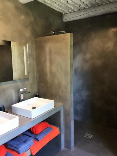 a bathroom with a white sink and red and blue towels at le mas de colongene in Faucon