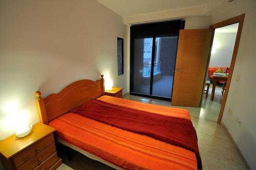 um quarto com uma cama com uma colcha laranja em Apartment Acacias em Lloret de Mar
