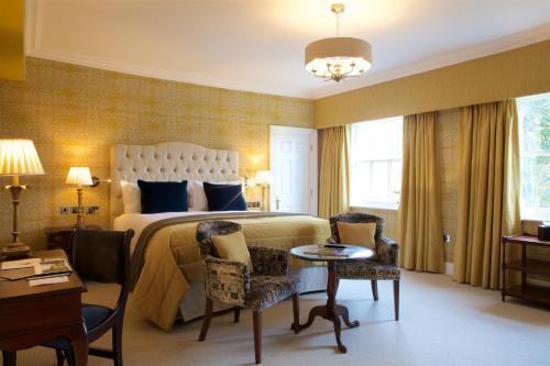 a bedroom with a bed and a table and chairs at Storrs Hall Hotel on the shore of Lake Windermere in Bowness-on-Windermere