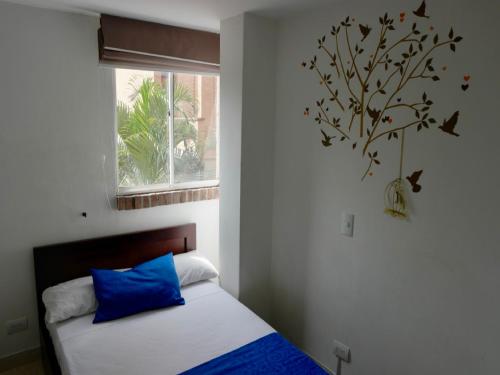 a bedroom with a bed with a blue pillow and a window at Amoblados Medellín Laureles in Medellín