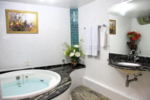 uma casa de banho com uma banheira grande e um lavatório em Hotel Riviera D Amazonia Belem Ananindeua em Belém