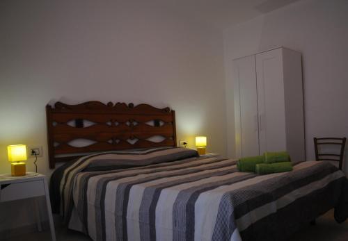 a bedroom with a bed with a striped blanket and two lamps at b&b Franzisca in Torpè