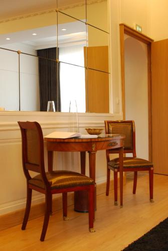 a dining room table with two chairs and a mirror at Hôtel Victor Hugo in Pontorson