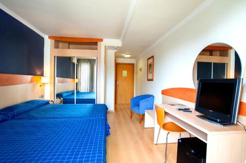 a hotel room with a blue bed and a television at Evenia President in Salou