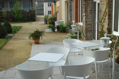 a row of white tables and chairs on a patio at Hôtel Victor Hugo in Pontorson