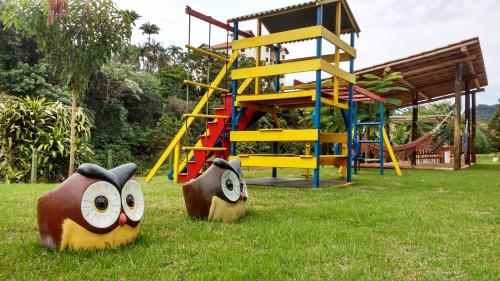 a playground with two wooden sculptures in the grass at Hotel Santiago in Lindóia