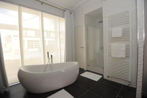 a white bath tub in a bathroom with a window at Hôtel Victor Hugo in Pontorson